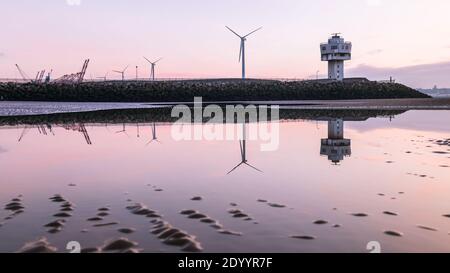 Les éoliennes, le phare et les grues de Seaforth Dock à Liverpool se reflètent dans un bassin d'eau sur la plage en décembre 2020. Banque D'Images