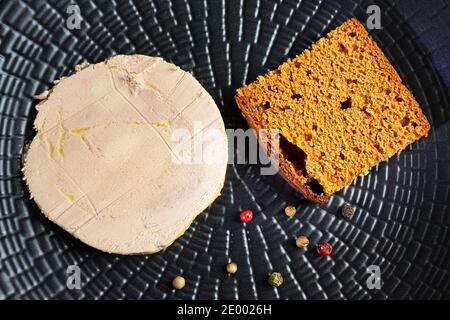 Foie gras de canard, pain d'épice et grains de poivre sur une assiette noire Banque D'Images