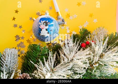 Taureau de jouet dans un chapeau de Père Noël sur un fond en bois foncé.branche d'arbre de Noël avec de petites boîtes-cadeaux et des balles. Bull comme symbole de la nouvelle année 202 Banque D'Images