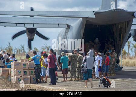 Guiuan, province de l'est du Samar, République des Philippines (nov 16, 2013) des marins du porte-avions déployé par l'avant de la Marine américaine USS George Washington (CVN 73), aux côtés de Marines et de civils philippins, aident à décharger des approvisionnements d'un Hercules HC-130 de l'Escadron de soutien de l'escadre maritime (SMSS) 172 à l'appui de l'opération Damayan. Le groupe de grève George Washington appuie la 3e Brigade expéditionnaire maritime pour aider le gouvernement philippin à répondre aux séquelles du Super Typhon Haiyan en République des Philippines. Photo par US Navy via ABACAPRESS.COM Banque D'Images