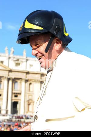 Le pape François a brièvement couvert sa calotte blanche traditionnelle avec un casque de pompier après qu'un groupe de pompiers lui ait remis la tête lors de sa visite habituelle parmi les pèlerins de la place Saint-Pierre au Vatican, le 16 octobre. 2013.le Pontife s'était arrêté pour saluer un groupe de pompiers volontaires italiens lorsqu'on lui a remis le casque noir et jaune. Il a demandé au groupe « Je le porte ? » Et après avoir été dit oui, il l'a fait avec le sourire, applaudi par les pompiers volontaires. Le pape François a été nommé personne de l'année par le magazine Time. Pendant ses neuf mois Banque D'Images