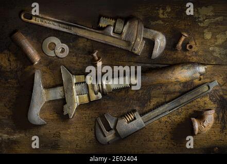 Anciennes clés à tube, écrous et boulons, tuyaux, raccords et rondelles sur l'ancienne table en bois Banque D'Images