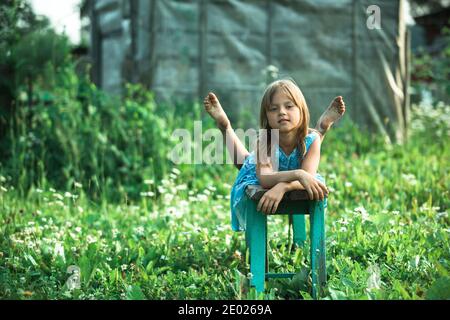 Petite fille posant dans la cour d'une maison de campagne. Banque D'Images