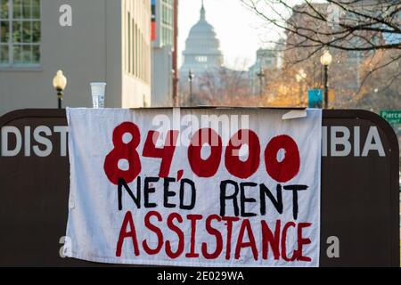 Washington, DC, Etats-Unis, 28 décembre 2020. Photo : un panneau pour sensibiliser les 84,000 ménages de DC incapables de se payer un loyer à bas prix, en partie en raison de la pandémie du coronavirus, est accroché à la DC Housing Authority, avec le dôme du Capitole des États-Unis au loin. Le panneau y a été placé lors de la manifestation pour l'équité en matière de logement, ainsi que 300 drapeaux, chacun représentant 280 ménages. La manifestation a été parrainée par des citoyens concernés de DC, migration Matters, jusqu'à ce que Freedom DC et les pays de la région noire comptent. Crédit : Allison C Bailey/Alay Live News Banque D'Images