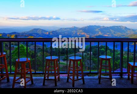 Tabouret en bois et rebord sur une terrasse en bois à un point de vue sur le bord de la route d'une chaîne de montagnes tropicales verdoyantes dans nord de la Thaïlande Banque D'Images