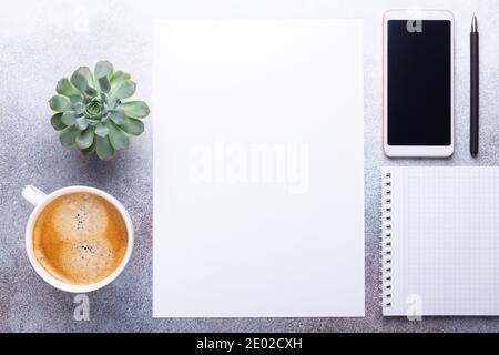 Espace de travail de bureau avec papier vierge, tasse de café, smartphone, vert succulent et stylo. Vue de dessus. Arrière-plan en pierre. Copier l'espace Banque D'Images