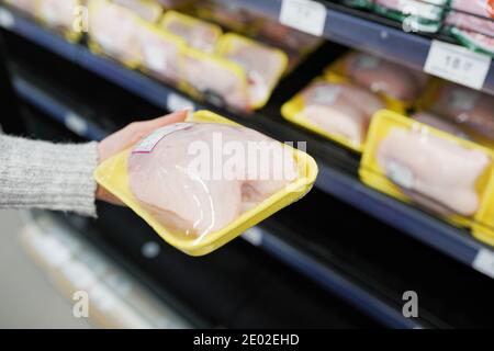 Femme choisissant de la viande de poulet emballée au supermarché Banque D'Images