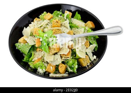 Salade César classique avec laitue romaine et copeaux de fromage parmesen servi dans un plat noir isolé sur fond blanc Banque D'Images