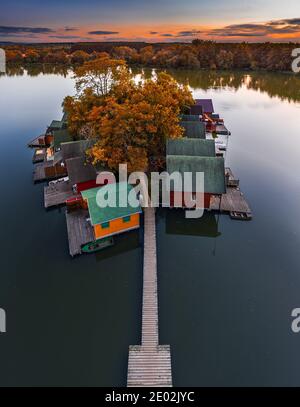 Tata, Hongrie - vue aérienne d'un magnifique coucher de soleil d'automne sur des chalets de pêche en bois sur une petite île au lac Derito (Derito-to). Le lac peut être fait Banque D'Images