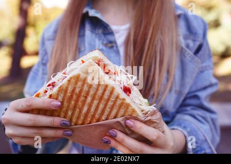 une fille mange du shawarma dans la rue. Restauration rapide Banque D'Images