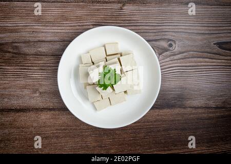 Tofu coupé en dés dans un plat sur fond de bois. Profondeur totale du champ. Concept alimentaire végétalien. Une alimentation saine Banque D'Images