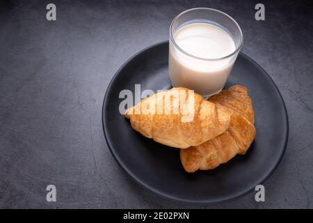 Délicieux croissants frais au lait de soja dans une assiette noire sur fond sombre. Petit déjeuner français. Croissants savoureux avec espace de copie Banque D'Images