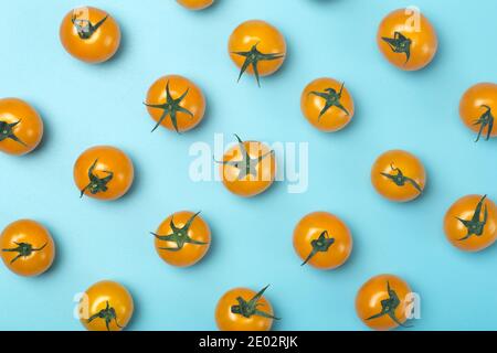 Tomates cerises sur fond bleu. Motif et fond minimal de tomates jaunes Banque D'Images