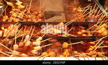 Divers types de nourriture oden sont cuits dans un pot chaud épicé divisé en grilles avec des boules, tofu, bâtonnets de fruits de mer et Chili. Cuisine japonaise en Chine. Banque D'Images