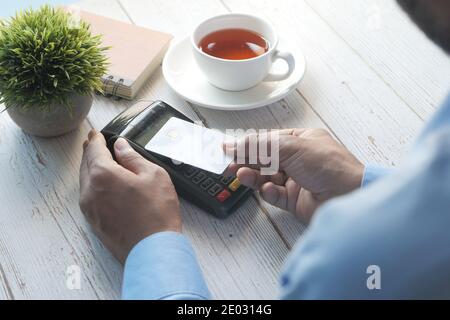 jeune homme effectuant le paiement sans contact avec carte de crédit , vue arrière Banque D'Images