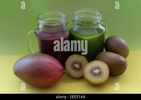 Smoothies aux fruits avec kiwis frais, et avocat.concept de boissons saines de détox vert et rouge dans le pot de mason sur fond vert et jaune créatif. Banque D'Images
