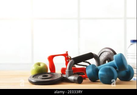 Accessoires pour l'entraînement sportif de gym avec bouteille d'eau et pomme sur plancher de lattes en bois. Vue avant. Composition horizontale. Banque D'Images