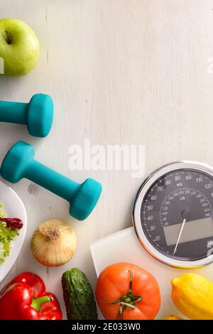 Une alimentation saine et un environnement sportif sur un bois blanc avec du calcaire et du ruban de mesure. Vue de dessus. Composition verticale. Banque D'Images