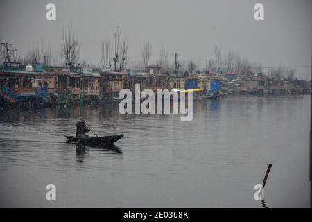 Srinagar, Inde. 29 décembre 2020. Un homme conduit son bateau pendant une chute de neige fraîche à Srinagar.une chute de neige fraîche a été enregistrée dans certaines parties de la vallée du Cachemire, y compris la capitale estivale, Srinagar, conduisant à la fermeture de la route nationale Srinagar-Jammu, ont déclaré les responsables. Crédit : SOPA Images Limited/Alamy Live News Banque D'Images