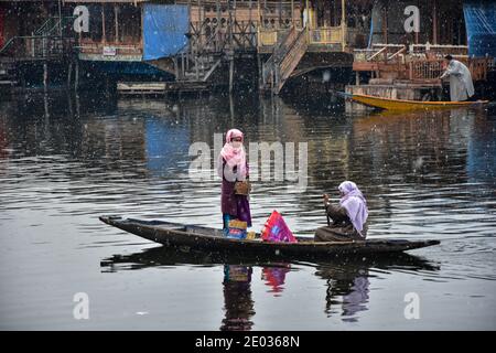 Srinagar, Inde. 29 décembre 2020. Une femme âgée fait passer un passager à bord de son bateau lors d'une chute de neige fraîche à Srinagar.des chutes de neige fraîches ont été enregistrées dans certaines parties de la vallée du Cachemire, y compris dans la capitale estivale, Srinagar, conduisant à la fermeture de la route nationale Srinagar-Jammu, ont déclaré les responsables. Crédit : SOPA Images Limited/Alamy Live News Banque D'Images