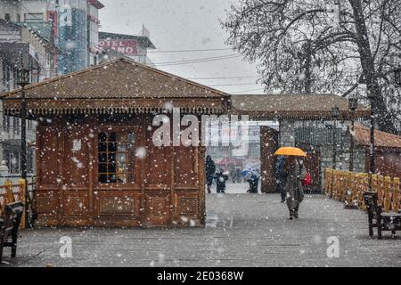 Srinagar, Inde. 29 décembre 2020. Un homme tient un parapluie pour le protéger des chutes de neige fraîches alors qu'il marche sur le pont à pied à Srinagar.des chutes de neige fraîches ont été enregistrées dans certaines parties de la vallée du Cachemire, y compris la capitale estivale, Srinagar, menant à la fermeture de la route nationale Srinagar-Jammu, ont déclaré les responsables. Crédit : SOPA Images Limited/Alamy Live News Banque D'Images