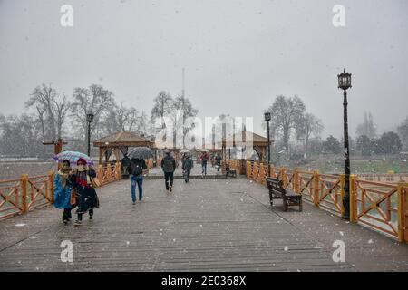 Srinagar, Inde. 29 décembre 2020. Les gens marchent en tenant des parasols pour les protéger de la neige fraîche à Srinagar.des chutes de neige fraîches ont été enregistrées dans certaines parties de la vallée du Cachemire, y compris la capitale estivale, Srinagar, menant à la fermeture de la route nationale Srinagar-Jammu, ont déclaré les responsables. Crédit : SOPA Images Limited/Alamy Live News Banque D'Images