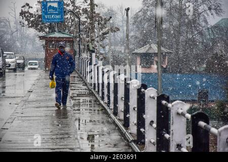 Srinagar, Inde. 29 décembre 2020. Un homme marche le long d'une rue pendant une chute de neige fraîche à Srinagar.une chute de neige fraîche a été enregistrée dans certaines parties de la vallée du Cachemire, y compris la capitale estivale, Srinagar, conduisant à la fermeture de la route nationale Srinagar-Jammu, ont déclaré les responsables. Crédit : SOPA Images Limited/Alamy Live News Banque D'Images