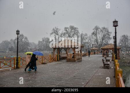 Srinagar, Inde. 29 décembre 2020. Les femmes cachemiri tiennent des parapluies alors qu'elles marchent à travers un pont à pied pendant les chutes de neige fraîches à Srinagar.des chutes de neige fraîches ont été enregistrées dans certaines parties de la vallée du Cachemire, y compris la capitale estivale, Srinagar, menant à la fermeture de la route nationale Srinagar-Jammu, ont déclaré les responsables. Crédit : SOPA Images Limited/Alamy Live News Banque D'Images