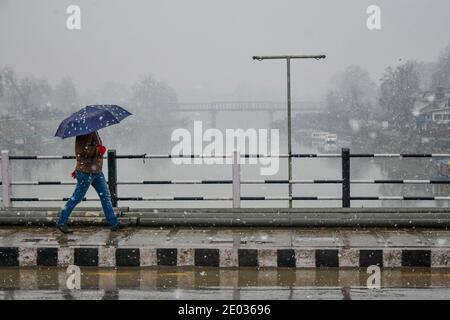 Srinagar, Inde. 29 décembre 2020. Un homme marche sous un parapluie alors qu'il marche à travers une route pendant une chute de neige fraîche à Srinagar.une chute de neige fraîche a été enregistrée dans certaines parties de la vallée du Cachemire, y compris la capitale estivale, Srinagar, menant à la fermeture de la route nationale Srinagar-Jammu, ont déclaré les responsables. Crédit : SOPA Images Limited/Alamy Live News Banque D'Images