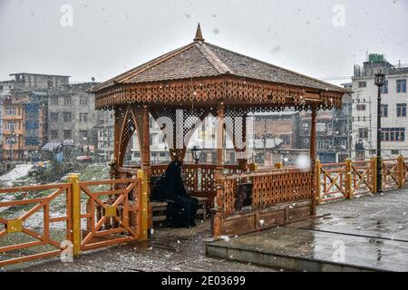 Srinagar, Inde. 29 décembre 2020. Une femme prend refuge sur un pont à pied pendant une chute de neige fraîche à Srinagar.des chutes de neige fraîches ont été enregistrées dans certaines parties de la vallée du Cachemire, y compris la capitale estivale, Srinagar, menant à la fermeture de la route nationale Srinagar-Jammu, ont déclaré les responsables. Crédit : SOPA Images Limited/Alamy Live News Banque D'Images