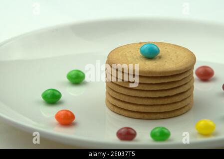 Gros plan des biscuits et des bonbons colorés sur une plaque en céramique blanche Banque D'Images