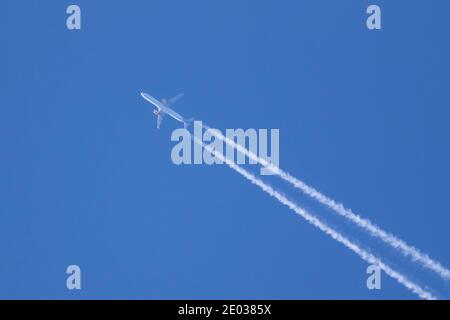 Un portrait d'un avion volant dans le ciel avec les sentiers de condensation, les contrails ou les pistes de vapeur derrière lui. Le plan traverse un cor Banque D'Images