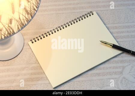 Ordinateur portable et stylo vierges éclairés par une lampe de bureau, un bureau de nuit ou un lieu d'étude Banque D'Images