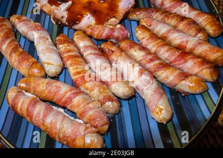 Plats de Noël traditionnels : cochons en couvertures, saucisses enveloppées de bacon, cuites, disposées sur une assiette Banque D'Images