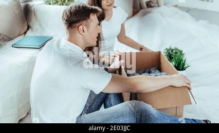 couple ouvrant une boîte en carton dans un nouvel appartement . Banque D'Images