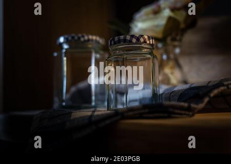 La vie sombre et moody encore de deux bocaux en verre vides avec des détails de carreaux bleus. Banque D'Images