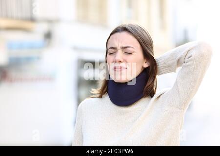 Femme stressée portant un corset de cou souffrant de douleurs cervicales dans la rue Banque D'Images