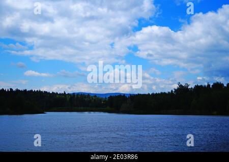 Lac dans les montagnes avec l'eau claire entouré par un dense forêt verte sous le ciel bleu Banque D'Images