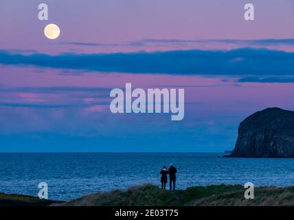 East Lothian, Écosse, Royaume-Uni, 29 décembre 2020. Météo au Royaume-Uni : une dernière lune complète pour 2020, appelée « Lune froide », s'élève au-dessus de Bass Rock dans le Firth of Forth au coucher du soleil avec un ciel rose et violet coloré Banque D'Images