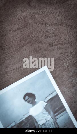 1965 photographie de la jeune femme portant une chemise et des lunettes debout sur la plage sur une surface en bois. Concept des années 1960, indépendant, rétro Banque D'Images