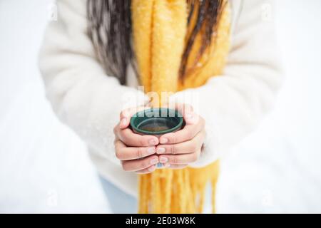 Gros plan de la femme qui chauffe avec du thé chaud dans elle mains debout à l'extérieur en hiver Banque D'Images