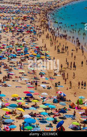 Vue depuis le dessus d'une plage pleine de personnes avec Nombreuses couleurs en Algarve Portugal Banque D'Images