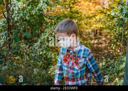 Jeune garçon marchant dans des bois portant un masque facial de protection Banque D'Images