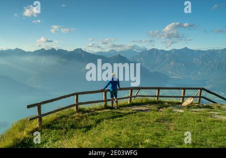 Personne de derrière avec un habillage bleu appuyé sur un bois clôture avec vue sur les montagnes Banque D'Images