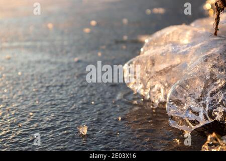 Glace transparente étincelante glace transparente en gros plan étincelant sur la surface du lac sauvage congelé à la lumière du coucher du soleil. Froid hiver nature fond Banque D'Images