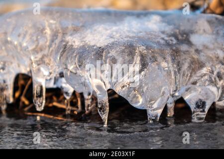 Glace transparente étincelante glace transparente en gros plan étincelant sur la surface du lac sauvage congelé à la lumière du coucher du soleil. Froid hiver nature fond Banque D'Images