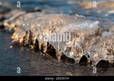 Glace transparente étincelante glace transparente en gros plan étincelant sur la surface du lac sauvage congelé à la lumière du coucher du soleil. Froid hiver nature fond Banque D'Images