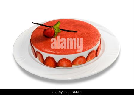 Cheesecake aux fraises, gâteau entier recouvert de crème de fraise rouge avec gousse de vanille et feuilles de menthe dans une assiette isolée sur fond blanc Banque D'Images
