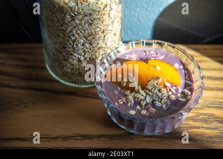 Açai smoothie, granola, graines, fruits frais dans un bol en verre sur une table en bois. Manger un bol de petit déjeuner sain. Vue de dessus. Photo de haute qualité Banque D'Images