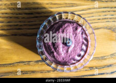 Açai smoothie, granola, graines, fruits frais dans un bol en verre sur une table en bois. Manger un bol de petit déjeuner sain. Vue de dessus. Photo de haute qualité Banque D'Images